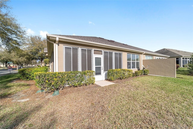 back of property featuring a lawn and stucco siding