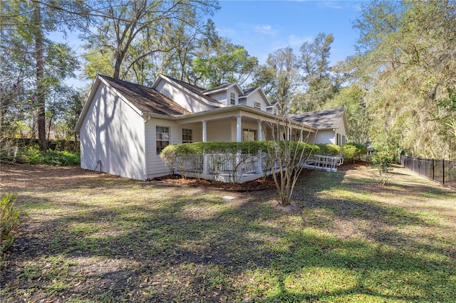 view of property exterior featuring a porch, a yard, and fence