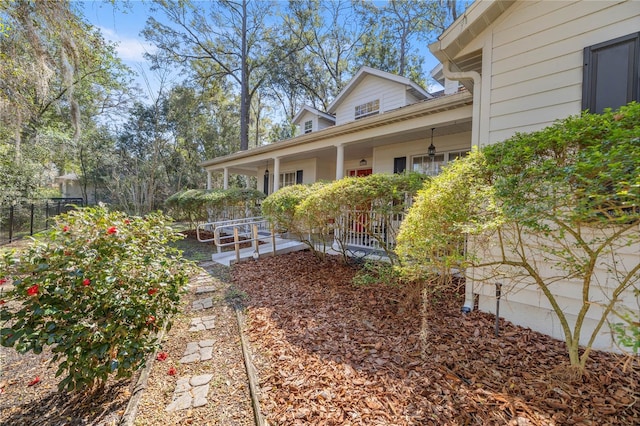 view of yard with covered porch and fence