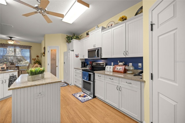 kitchen with stainless steel appliances, white cabinetry, a kitchen island, and light wood-style flooring