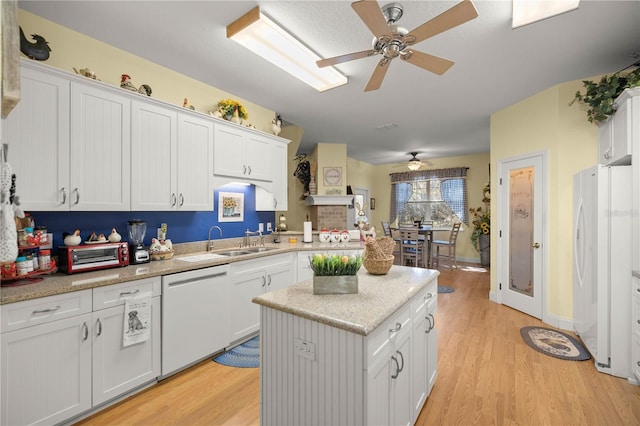 kitchen with light wood-style flooring, white cabinetry, a kitchen island, a sink, and white appliances