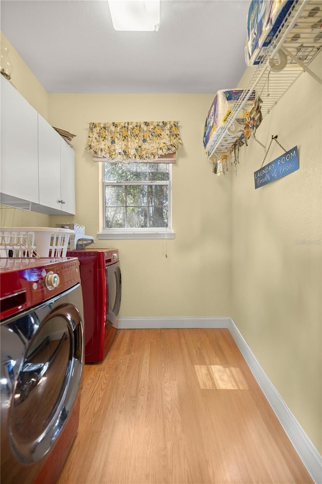 washroom featuring light wood finished floors, independent washer and dryer, cabinet space, and baseboards