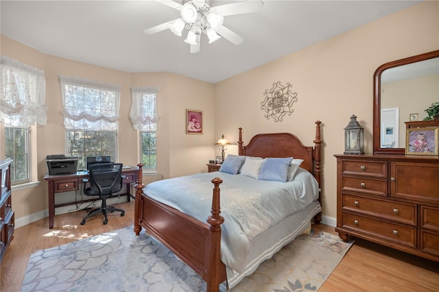 bedroom featuring light wood finished floors, a ceiling fan, and baseboards