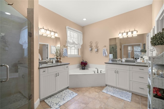 full bath featuring a garden tub, two vanities, a sink, and a shower stall