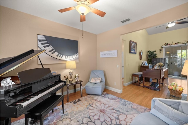 sitting room featuring a ceiling fan, wood finished floors, visible vents, and baseboards