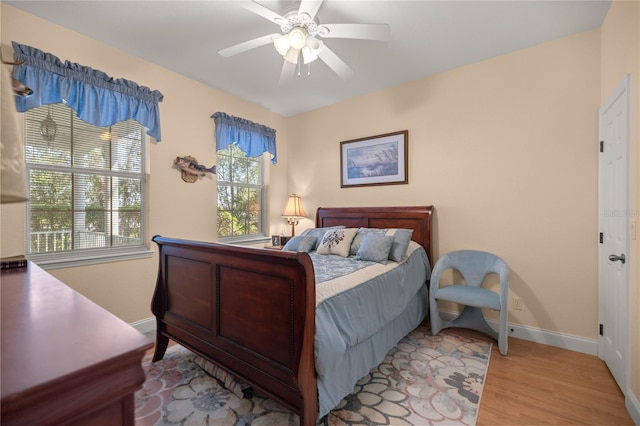 bedroom with light wood-style floors, ceiling fan, and baseboards