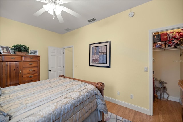 bedroom featuring wood finished floors, visible vents, baseboards, a spacious closet, and a closet