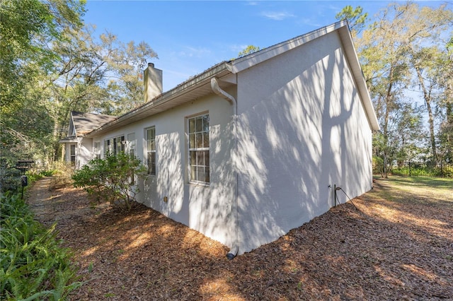 view of side of property featuring a chimney and stucco siding