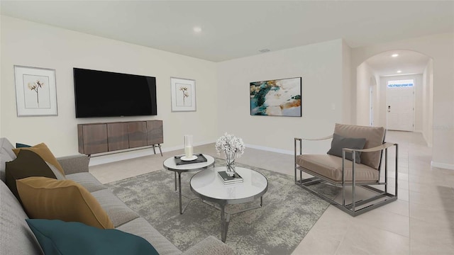 living room with light tile patterned floors, baseboards, arched walkways, and recessed lighting