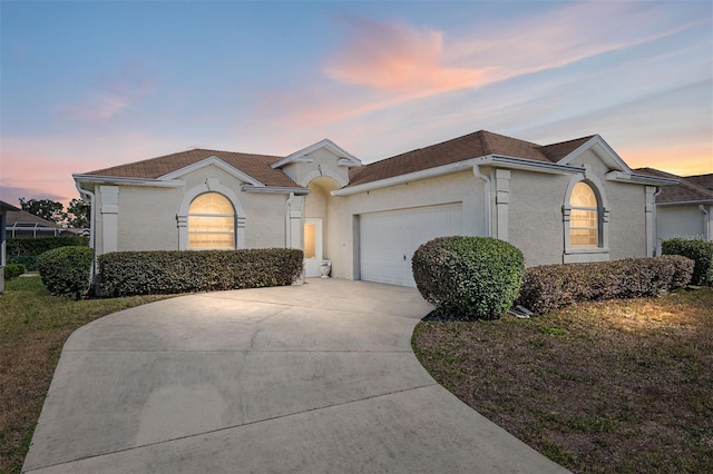 mediterranean / spanish home with concrete driveway, a front yard, an attached garage, and stucco siding