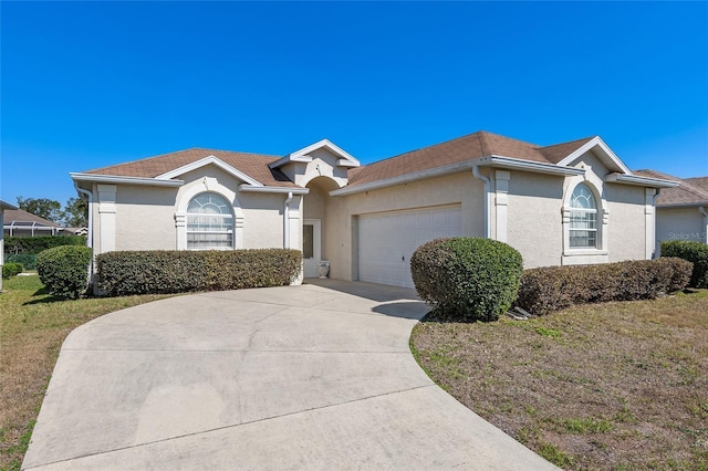 ranch-style home featuring an attached garage, a front yard, concrete driveway, and stucco siding