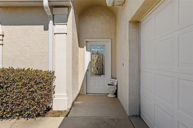 doorway to property featuring a garage and stucco siding