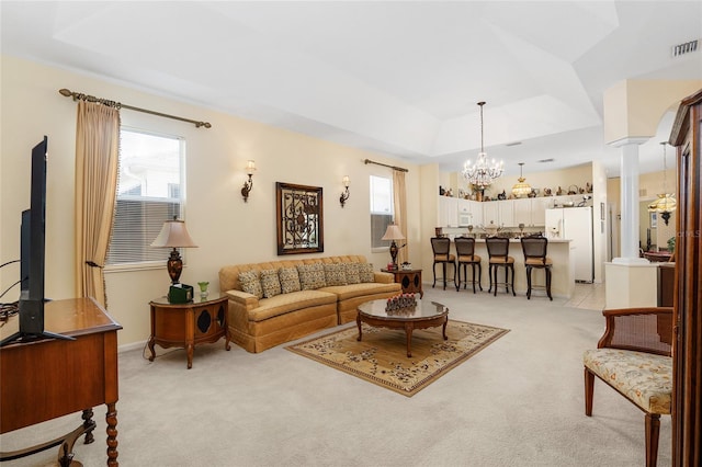 living area with a notable chandelier, light carpet, visible vents, a tray ceiling, and ornate columns