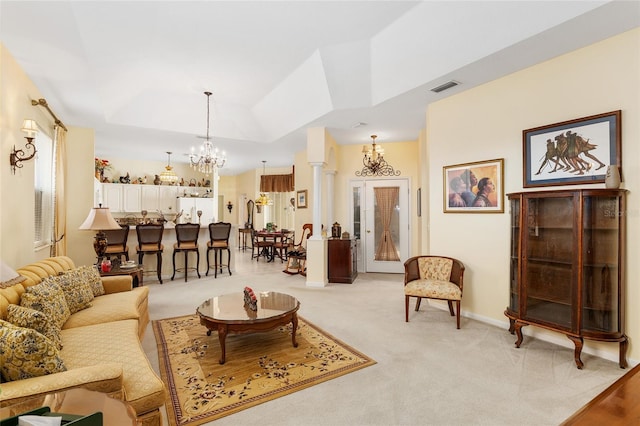 living room with a chandelier, light carpet, visible vents, a tray ceiling, and ornate columns