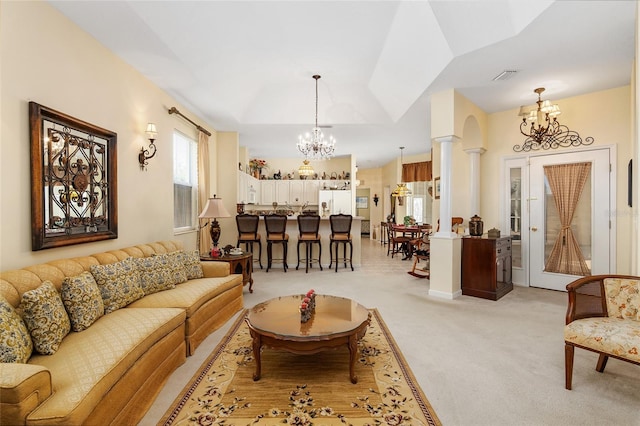 living area featuring visible vents, light colored carpet, decorative columns, and an inviting chandelier