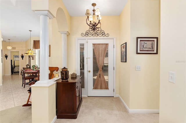 entrance foyer featuring light tile patterned floors, decorative columns, baseboards, and light colored carpet