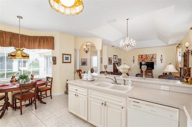 kitchen featuring arched walkways, white dishwasher, a sink, ornate columns, and pendant lighting