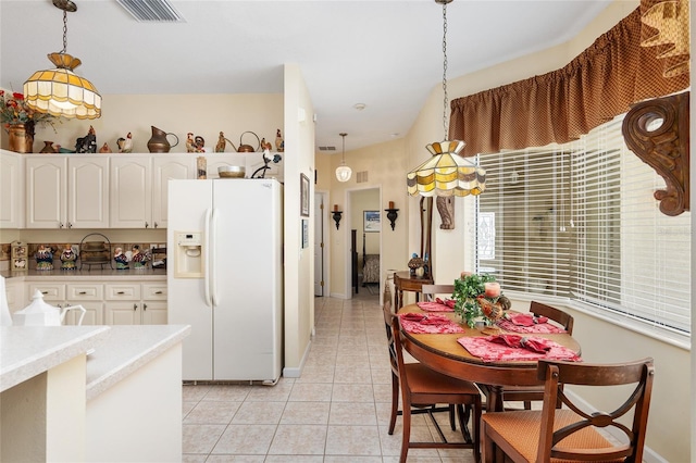 kitchen featuring white fridge with ice dispenser, pendant lighting, visible vents, and light tile patterned floors