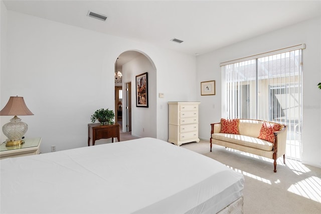 bedroom with visible vents, arched walkways, and light colored carpet