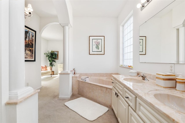 bathroom featuring a garden tub, a sink, ornate columns, and double vanity