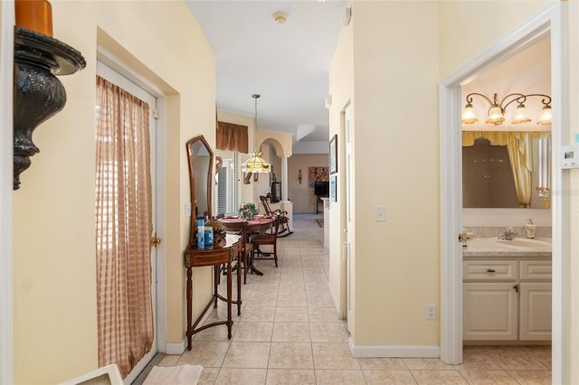 hallway featuring light tile patterned flooring, a sink, and baseboards