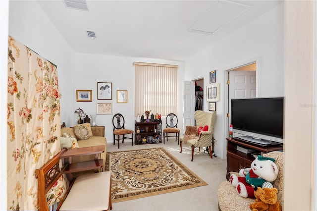 living area featuring attic access, light colored carpet, and visible vents