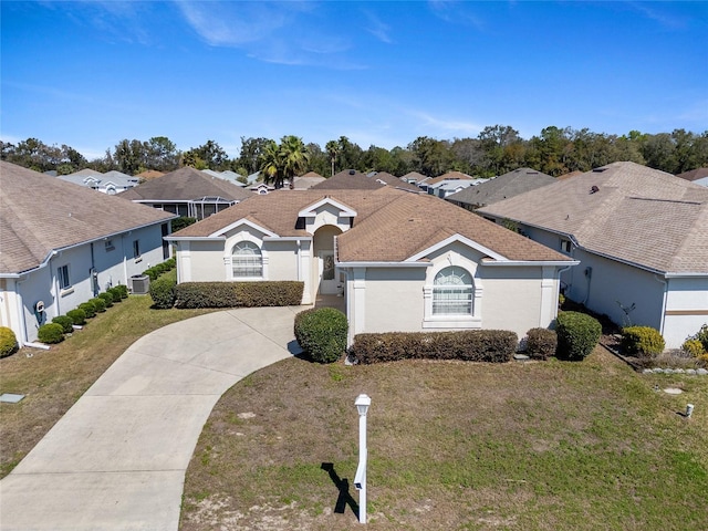 ranch-style home with a shingled roof, concrete driveway, a residential view, a front yard, and stucco siding