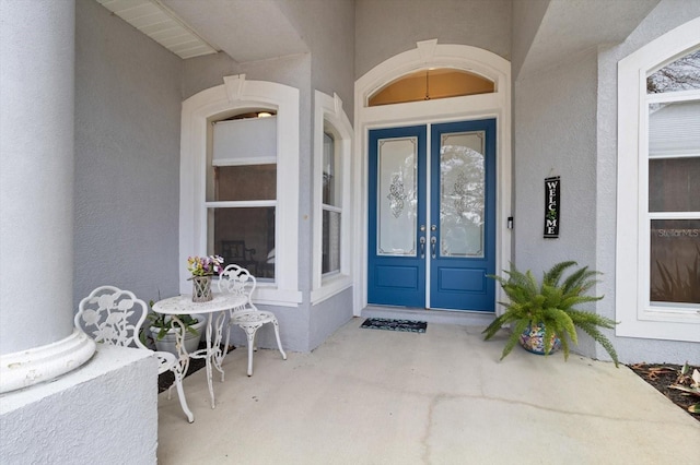 view of exterior entry featuring french doors and stucco siding