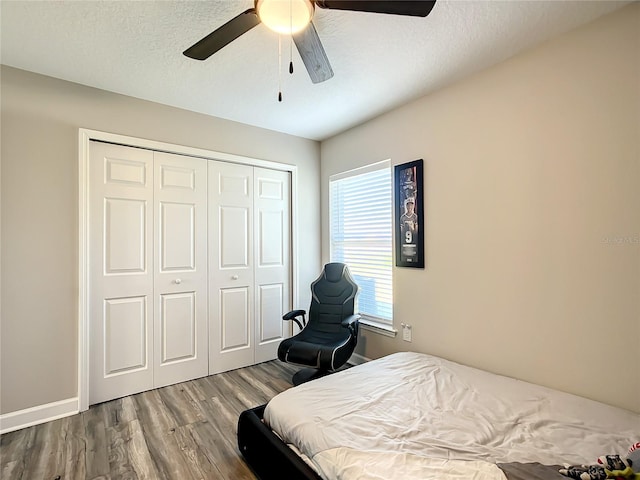 bedroom with a closet, ceiling fan, a textured ceiling, wood finished floors, and baseboards