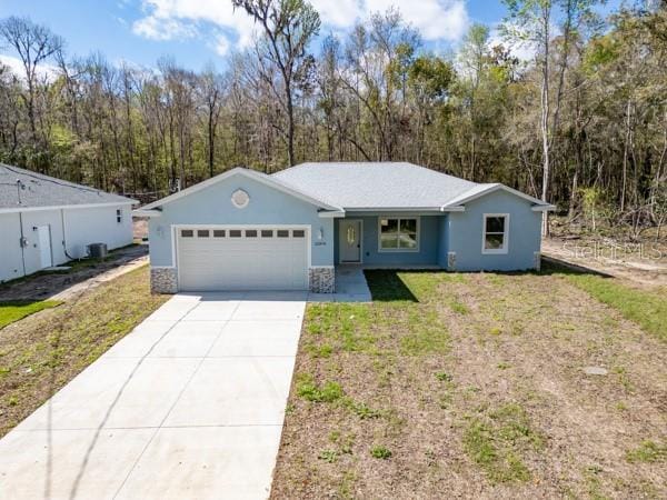 single story home with an attached garage, driveway, a front lawn, and stucco siding