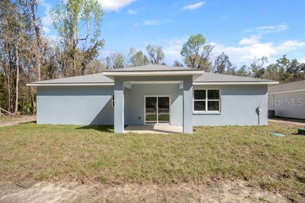 back of property with a lawn, a patio, and stucco siding