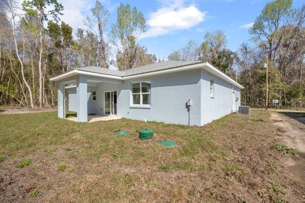 view of front of property featuring a patio area, central AC, a front lawn, and stucco siding