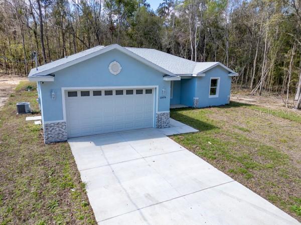 single story home with a garage, stone siding, driveway, and stucco siding
