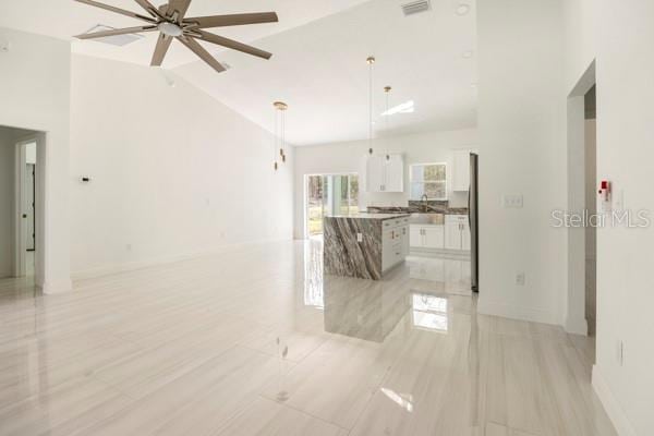 interior space featuring ceiling fan, high vaulted ceiling, visible vents, and baseboards