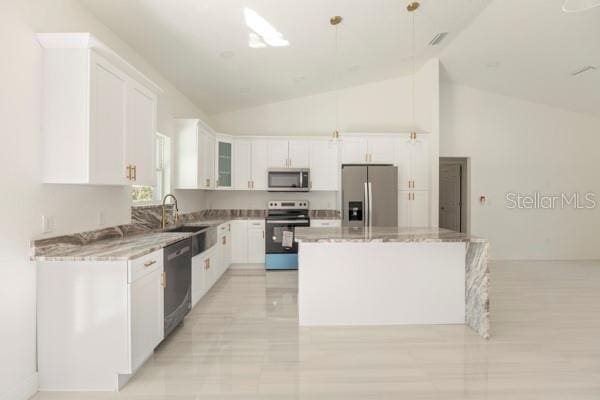 kitchen featuring a kitchen island, light stone countertops, stainless steel appliances, white cabinetry, and a sink