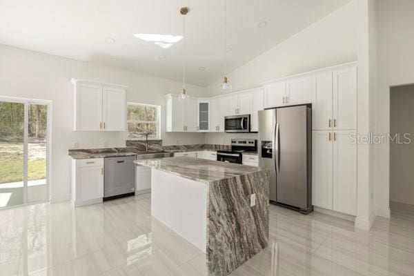 kitchen featuring stainless steel appliances, plenty of natural light, white cabinets, and a center island