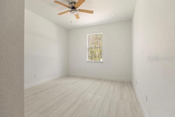 empty room featuring light wood-type flooring, ceiling fan, and baseboards