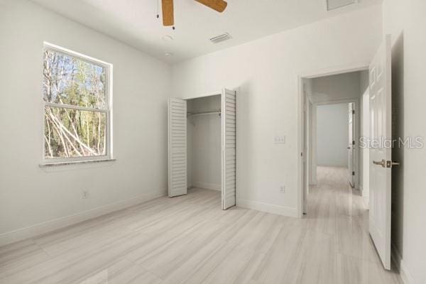 unfurnished bedroom with a closet, visible vents, ceiling fan, light wood-type flooring, and baseboards