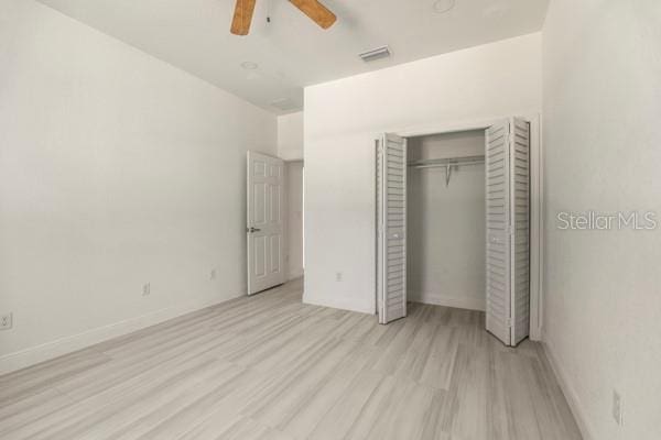 unfurnished bedroom featuring light wood finished floors, a closet, visible vents, ceiling fan, and baseboards