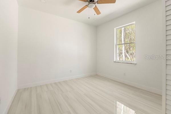 spare room featuring light wood-style floors, ceiling fan, baseboards, and built in features