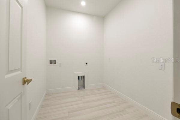 clothes washing area featuring laundry area, baseboards, light wood-style flooring, hookup for a washing machine, and hookup for an electric dryer