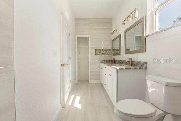 bathroom with toilet, baseboards, and vanity