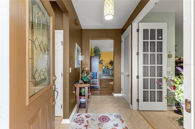 foyer with baseboards and light tile patterned flooring