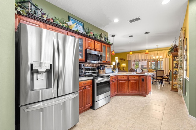 kitchen with a peninsula, visible vents, appliances with stainless steel finishes, glass insert cabinets, and pendant lighting