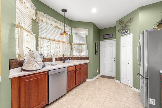 kitchen with stainless steel appliances, a sink, baseboards, light countertops, and pendant lighting