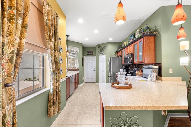 kitchen with stainless steel appliances, light countertops, visible vents, glass insert cabinets, and a peninsula