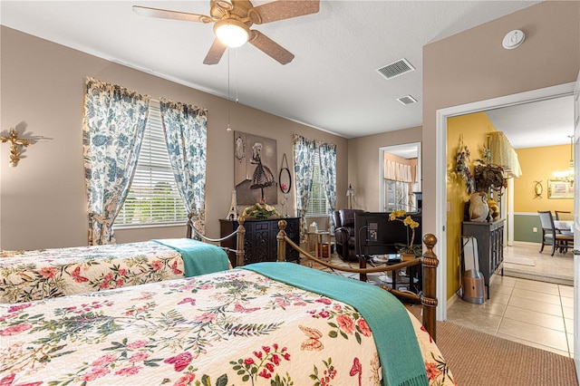 tiled bedroom with a textured ceiling, baseboards, visible vents, and a ceiling fan