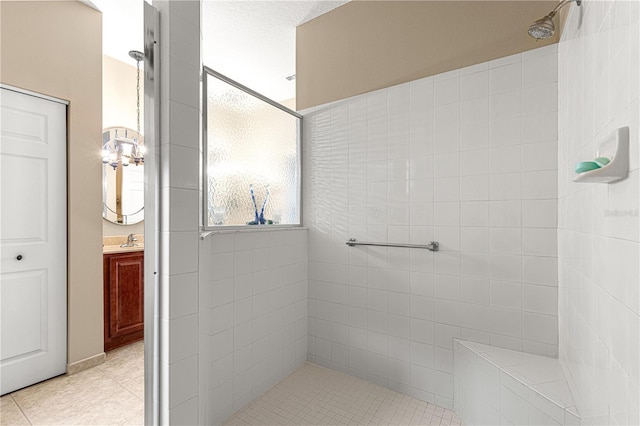 full bath with tile patterned floors, tiled shower, and vanity