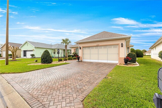 single story home featuring decorative driveway, an attached garage, a front lawn, and stucco siding