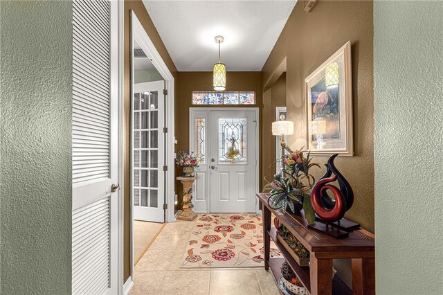 foyer entrance featuring light tile patterned floors and a textured wall